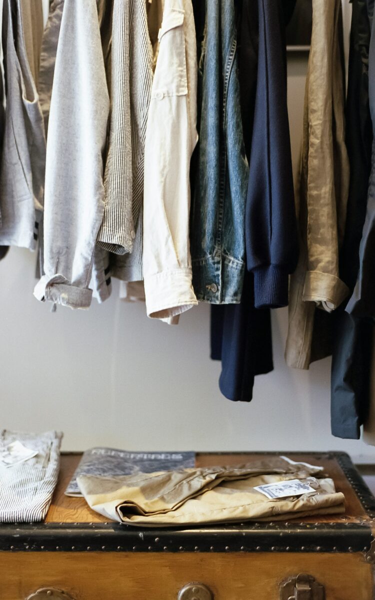 stock photo of clothing hanging on a bar with a shelf below holding folded clothing. Closet, fashion wardrobe, minimalism, clothing rack Used in the article You Can Go Your Own Way