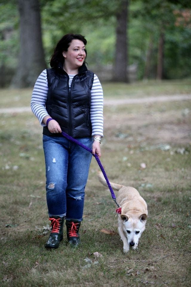 Bogs Boot Review and Our Dog Cindy 1 woman in jeans, a striped shirt, and black vest walking a midsized blonde dog on a leash
