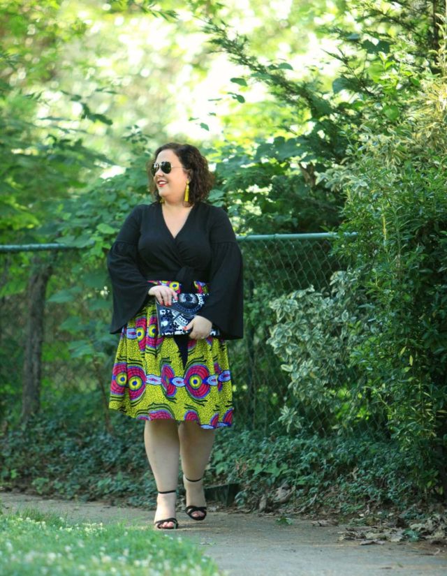 Wardrobe Oxygen in an ELOQUII wrap top with bell sleeves and an yellow Ankara midi skirt