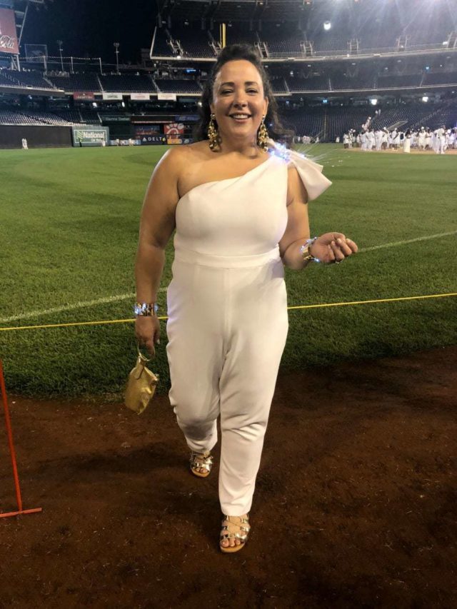 Alison Gary of Wardrobe Oxygen in a white one-shouldered jumpsuit at Diner en Blanc Washington DC 2018 at Nationals Park