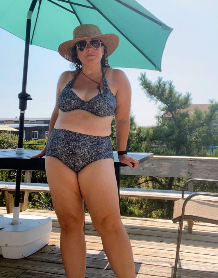 Alison Gary of Wardrobe Oxygen in a Freya bikini and Lack of Colour straw hat. She is standing on a wooden deck at Davis Park, Fire Island