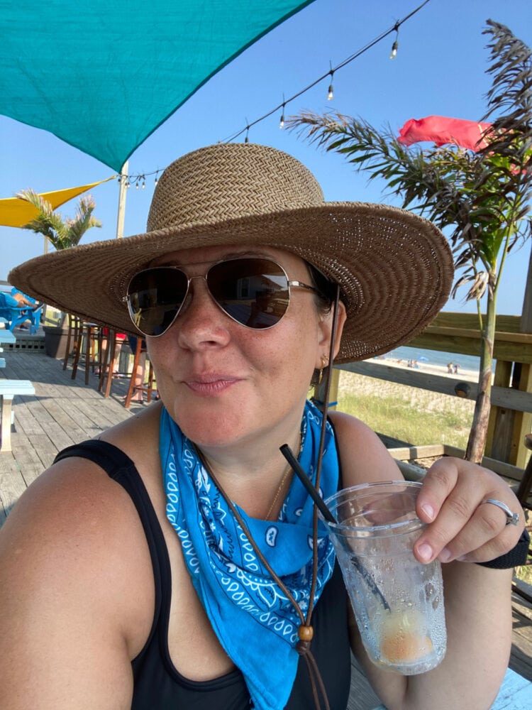 Alison Gary of Wardrobe Oxygen sitting on a deck in Fire Island, sipping on a cold beverage
