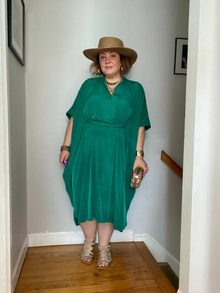 Alison wearing the green ever by X dress styled like a caftan with a straw hat and gladiator sandals
