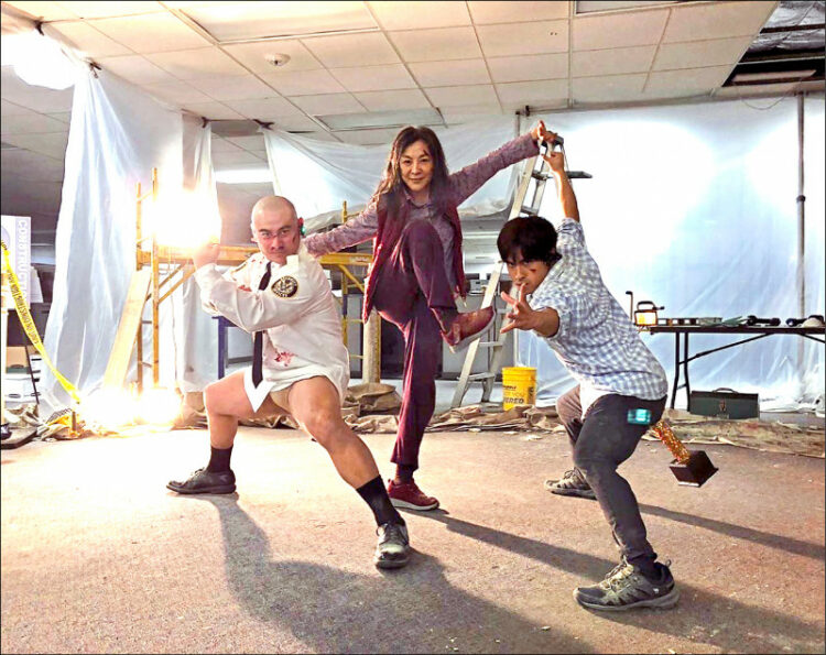 A scene from the movie Everything Everywhere All at Once with Michelle Yeoh and two men with awards stuck up their butts