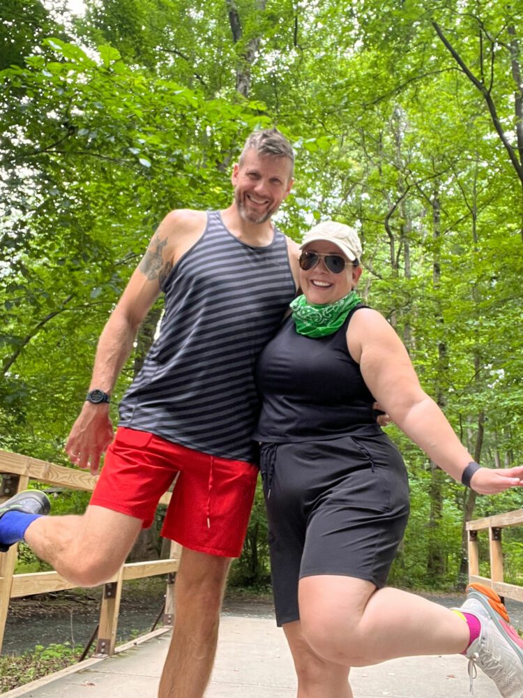 Alison Gary of Wardrobe Oxygen and her husband on a bridge in a wooded park, both wearing Zenergy shorts from Chico's