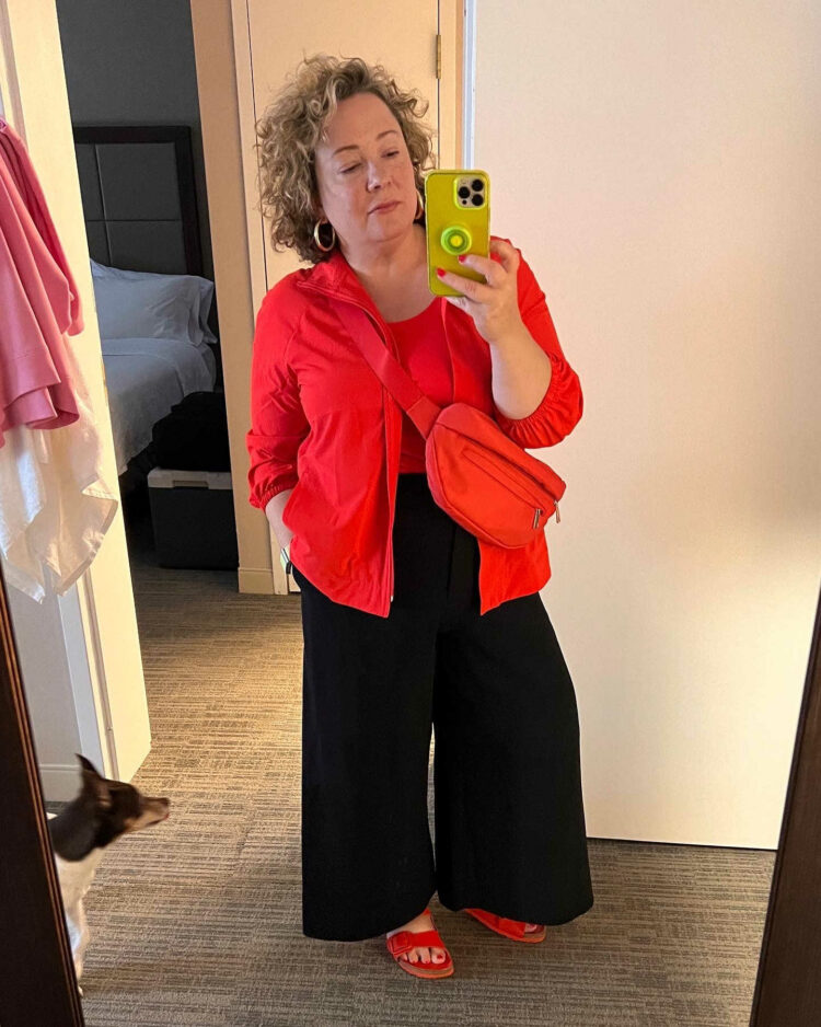 Woman in a tomato red Chico's Zenergy Neema fabric windbreaker with a Chico's microfiber tank in the same color.