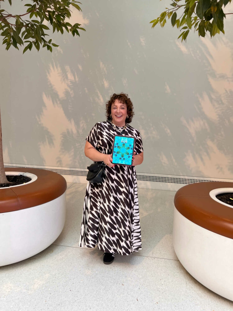 Alison in a brown print silk maxi dress from Banana Republic, holding an iPad