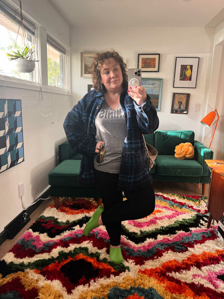 Alison in a blue plaid shacket from L.L. Bean with black Old Navy leggings and a gray t-shirt that says Feminist on it.
