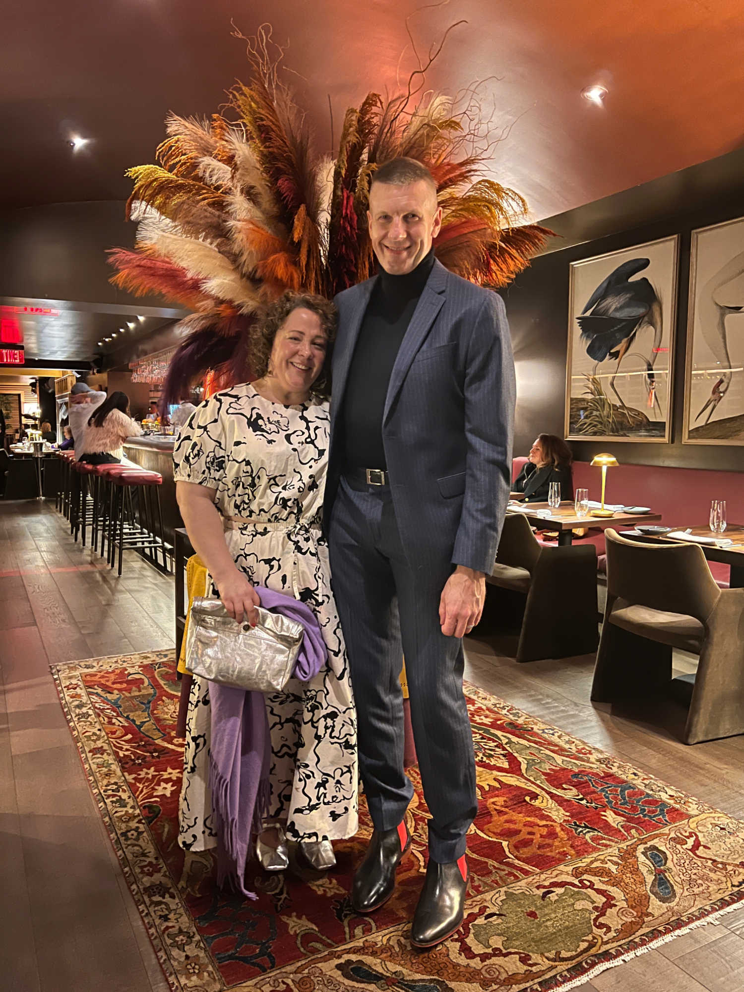 Alison and Karl Gary, a petite brunette and tall blonde man both over 40, standing together at the hostess stand at L'Avant-Garde in Georgetown, DC