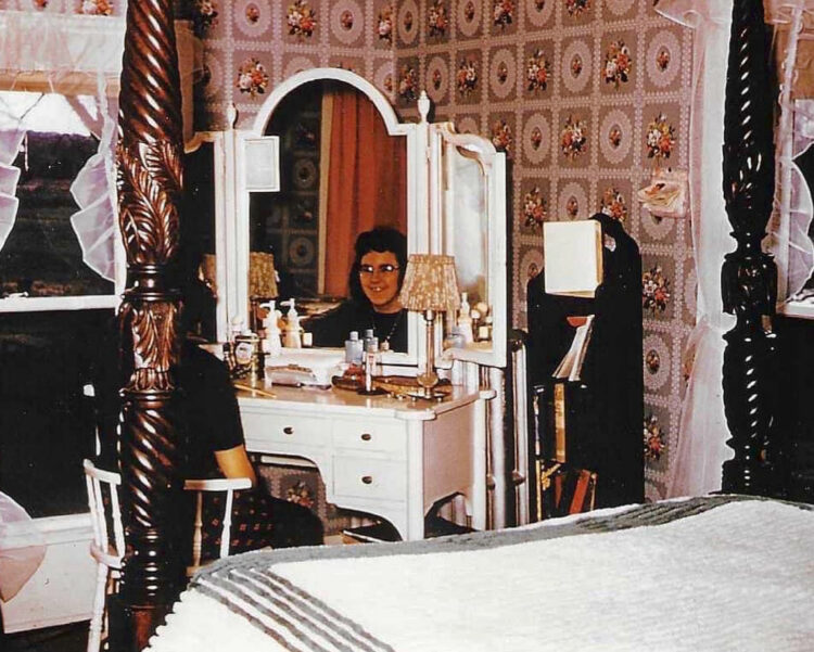 my mom as a young adult sitting at her white dressing table in her childhood bedroom